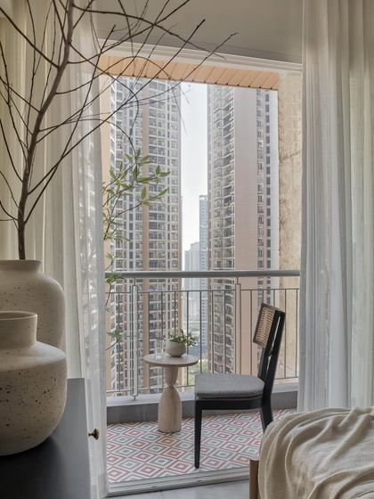 Stepping from the bedroom’s sleek concrete finish to the balcony’s inviting floor, a blend of grey and rustic brown tiles adds a touch of nature and extends the living space.