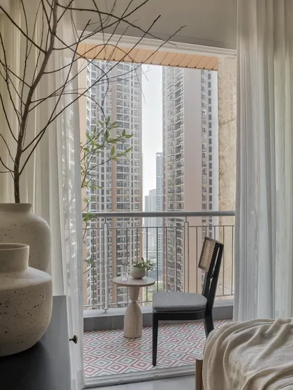 Stepping from the bedroom’s sleek concrete finish to the balcony’s inviting floor, a blend of grey and rustic brown tiles adds a touch of nature and extends the living space.