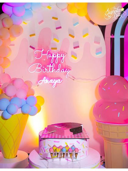The ice cream party setup at night, with the neon 'Happy Birthday' sign glowing. The lighting adds a whole new dimension to the decor.