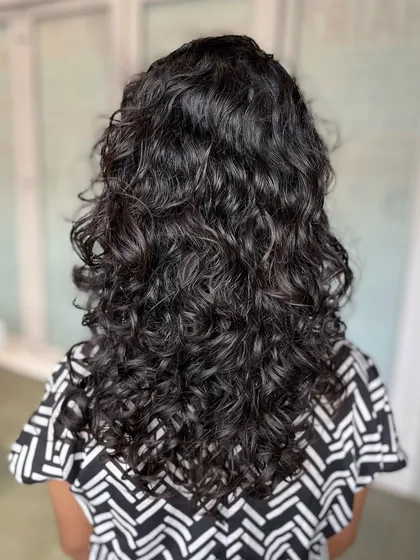 The back view of the curly haircut, showcasing the volume and definition achieved through our specialized cutting techniques.