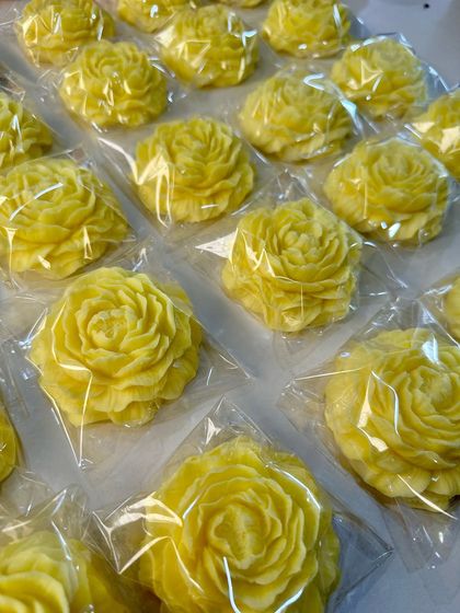A batch of beautiful, handcrafted yellow peony soaps, individually wrapped and ready to be part of a return gift hamper. Each one is a little piece of sunshine.