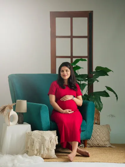 A pop of color with a vibrant red dress and a teal armchair. This studio setup is perfect for clients who want a bright and cheerful maternity session.