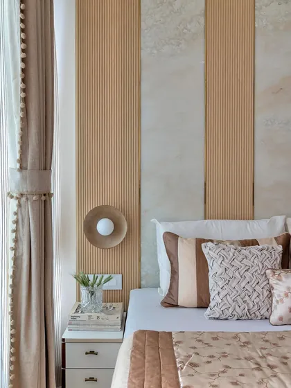 The bedside styling in this room is simple yet effective. A modern brass sconce provides reading light, while a small plant in a glass vase adds a fresh, natural element.