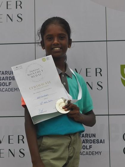 A young girl proudly displays her certificate and medal. These early successes build confidence and a lifelong love for the game.