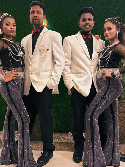 Our dance troupe ready for a show. This picture showcases one of our coordinated costume sets, featuring black tops, sparkling pants, and white blazers for the men.