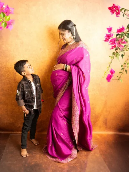 A beautiful portrait of a mother to be in a traditional pink saree with her son. This image captures the sweet anticipation and the loving relationship between them before the new baby arrives.