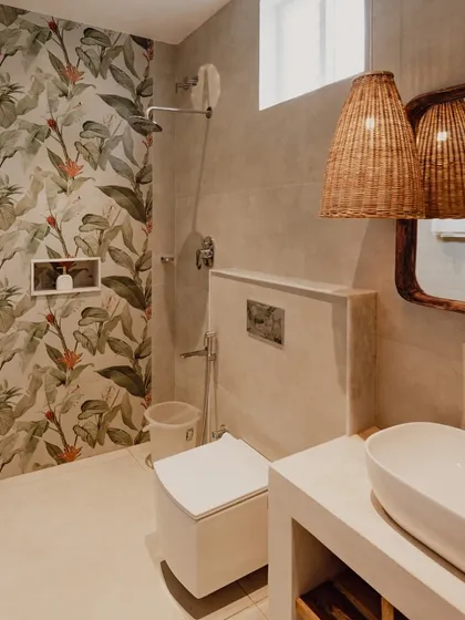 This bathroom brings the outdoors in with a tropical-themed accent wall. The space is completed with a vessel sink and woven pendant lights, continuing the villa's natural aesthetic.