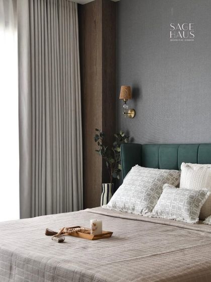 A wider view of the bedroom, showing how the dark accent wall and green headboard are balanced by the light-colored bedding and sheer curtains. The space feels both grounded and elevated.
