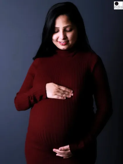 A gentle smile from the mother-to-be as she cradles her bump in this classic, elegant studio maternity portrait.