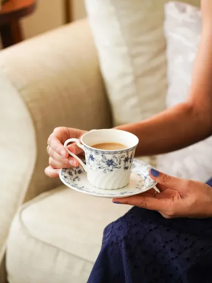 A lifestyle shot of a woman enjoying a cup of tea in a beautiful floral-patterned ceramic cup, creating a relatable and serene moment.