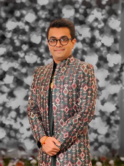 A groom looking confident in his modern Indo-Western jacket with classic motifs. The black and white photo highlights the sharp cut and intricate pattern of the garment.