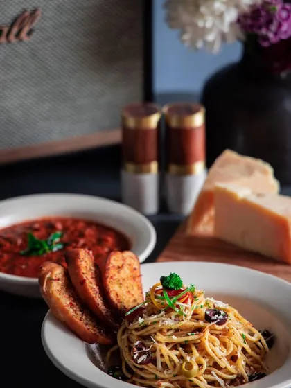 A classic Italian meal featuring spaghetti aglio e olio and a side of arrabbiata sauce with garlic bread.