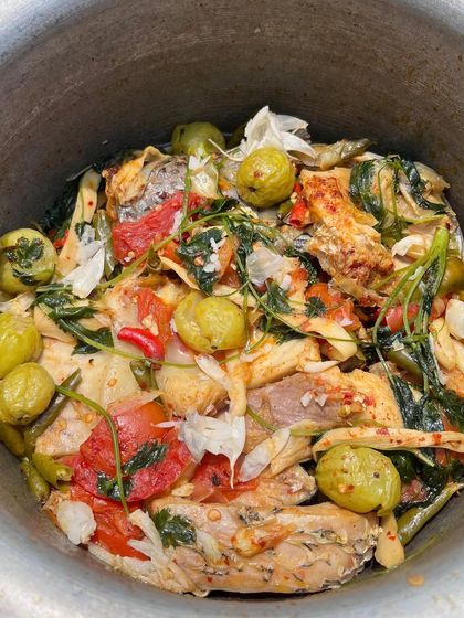 A pot of our home-style fish curry, cooked with bitter eggplant, tomatoes, and wild herbs. This oil-free preparation is light, healthy, and full of the natural flavors of the ingredients.