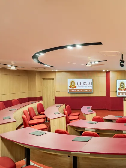 A tiered, semi-circular classroom at GL Bajaj University. The bold red color scheme and curved desks are designed to stimulate engagement, while the layout ensures clear sightlines for every student.