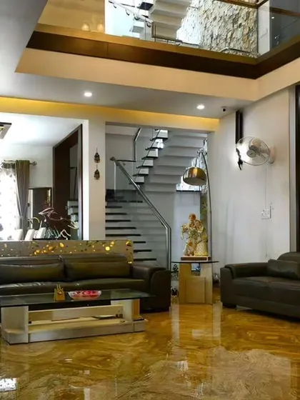 A view of a spacious, double-height living room we designed, featuring marble flooring and a modern staircase. This project showcases our work on a larger, more luxurious scale.