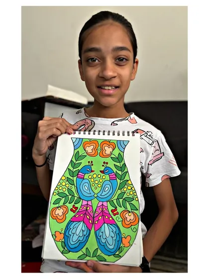 A student holds her beautiful vase design, a required topic for the intermediate grade exam. We learn about symmetry, pattern, and colour harmony.