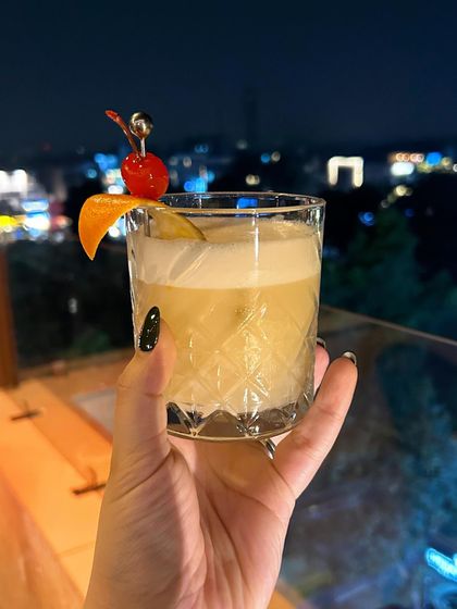 A classic whiskey sour against the Delhi skyline from the terrace at Staple. This photo combines a great cocktail with a stunning view, selling the entire experience.