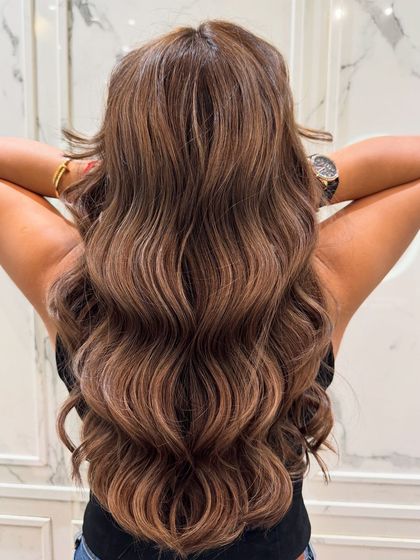 This shot captures the full length and dimension of the walnut balayage, styled in soft waves.