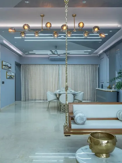This view showcases the open-plan layout, where the living and dining areas flow seamlessly. The traditional wooden swing adds a touch of Indian heritage to the modern design.
