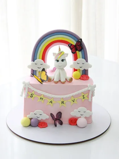 Another view of the unicorn half birthday cake, showing the cheerful rainbow and smiling clouds.