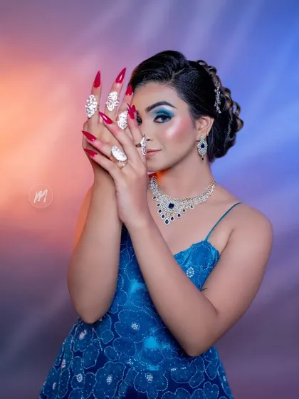 A creative pose with the hands, drawing attention to the dramatic nails and the eye makeup.