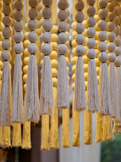 A close-up of the custom tassel chandelier, showing the detail of the wooden beads and thick cotton tassels.