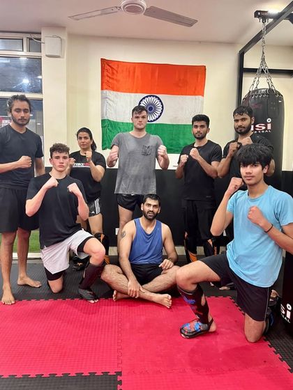A group of our members posing in front of the Indian flag in our dojo, showing pride in our roots and our team.