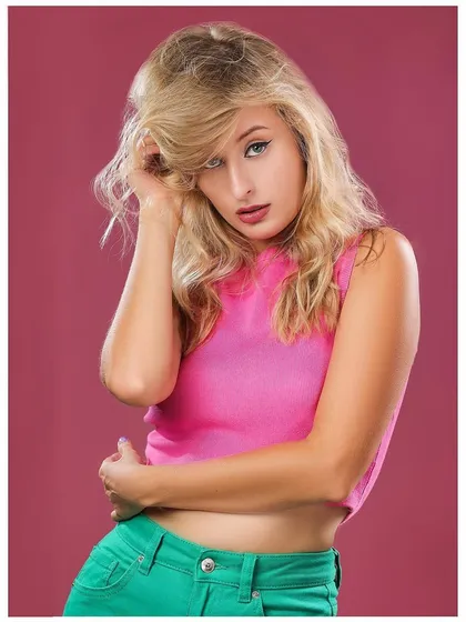 A vibrant portrait with a model in a pink top and green pants against a magenta background, creating a bold color-blocked look.