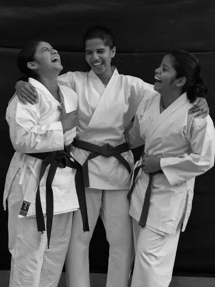 A moment of laughter and friendship between three black and brown belt students. Our dojo is a place of serious training, but also of joy and camaraderie.