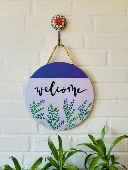 Add a charming touch to your entrance with our hand-doodled 'Welcome' wooden sign. Hung with durable jute twine and wooden beads, this sign brings a rustic and artistic vibe to your doorway.