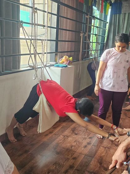 This student is using a pelvic sling and wall ropes to experience a suspended Downward-Facing Dog, which helps to traction the spine and release tension in the lower back.