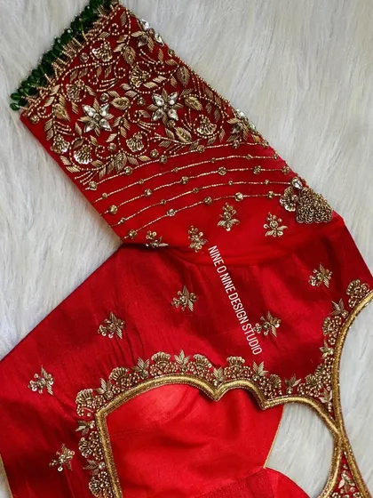 A masterpiece for our bride Madhuri. This classic red bridal blouse is heavily embroidered with zardosi and stone work, featuring a beautiful heart-shaped cutout on the back. The sleeves are a canvas of intricate floral patterns, making it a truly royal piece.