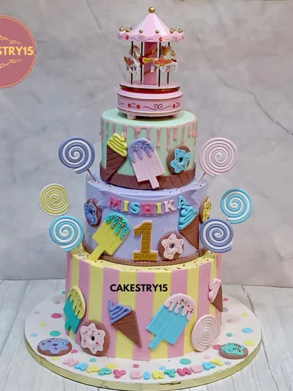 Step right up to this whimsical three-tier carousel and candyland cake. This colorful creation is decorated with fondant lollipops, ice cream cones, and donuts, and is crowned with a beautiful, classic carousel topper.