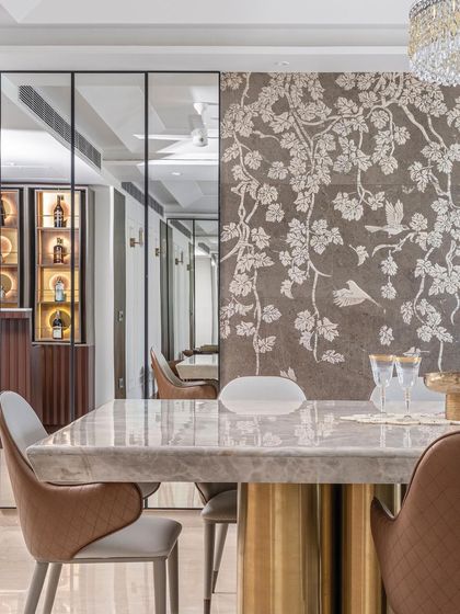 The reflection in the mirrored wall panels reveals the bar area, demonstrating how we use mirrors to create visual connections and enhance the perception of space in our interior layouts.