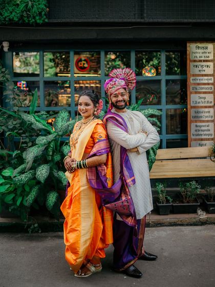 A slightly different angle of the couple's stylish back-to-back pose, emphasizing the rich colors and textures of their traditional wedding clothes.