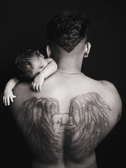 A powerful black and white portrait capturing the bond between a father and his newborn. The dramatic lighting and composition create a truly artistic and memorable image.
