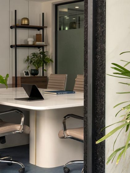 Another peek into the conference room, this time framed by a dark stone-clad column and a leafy plant, adding layers of texture and depth.