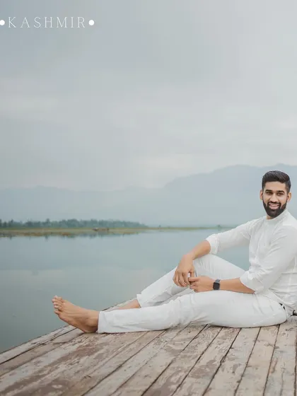 A relaxed portrait of the groom-to-be sitting on a dock by Dal Lake, Kashmir.