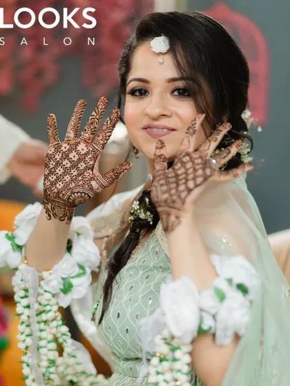 A glimpse into our bridal beauty services. This client is glowing for her Mehendi ceremony with intricate henna, soft, romantic makeup, and a beautifully styled floral braid. We create bespoke looks for every wedding event.