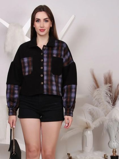 An international model styled in a plaid and black patched shirt with shorts, demonstrating a trendy look for a fashion e-commerce site.