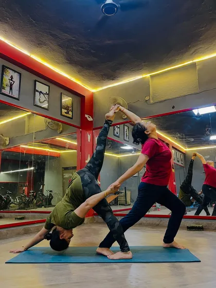Partner yoga helps improve flexibility and balance while fostering connection. In my workshops, I teach accessible yet impressive poses like this assisted downward dog leg lift, perfect for colleagues to build rapport.