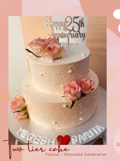 A lovely two-tier cake for a 25th anniversary, personalized with the couple's names. The design is simple yet elegant, with fresh roses and pearl details.