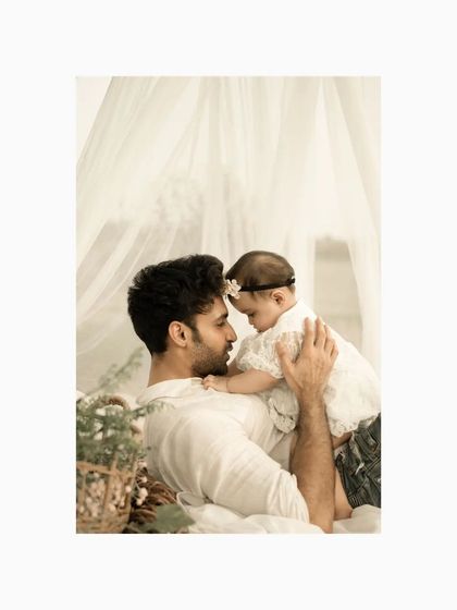 A daughter's first love is often her dad. This tender image shows a father and his baby girl sharing an intimate moment, their foreheads touching, in a soft, dreamy studio setup.