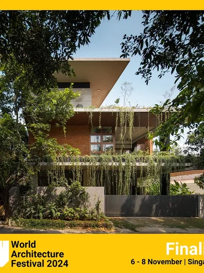 The full facade of the 'House of Greens', an award-finalist project. The cantilevered roof and deep-set balconies are designed to respond to the local climate, providing shade while maximizing views of the surrounding greenery.