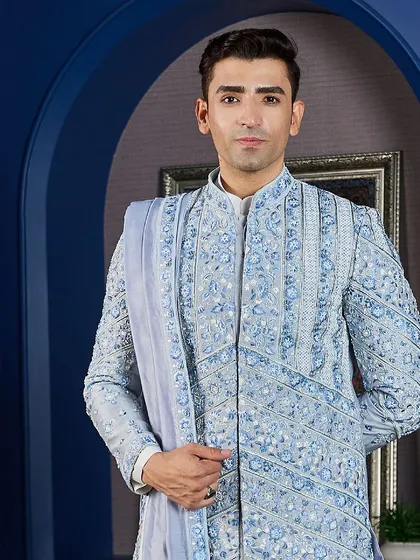 A detailed shot of the powder blue sherwani, highlighting the dense, handcrafted embroidery on the chest and shoulders. The matching stole adds another layer of sophistication.