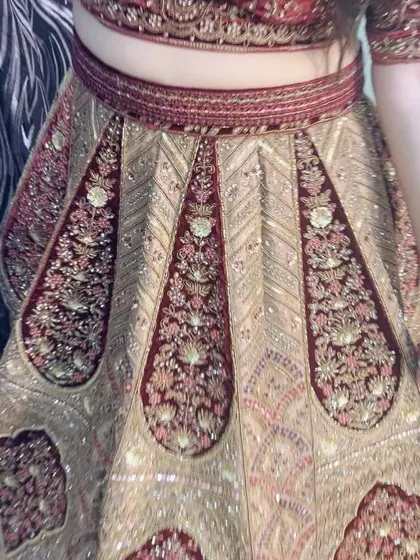 A close-up shot of a client wearing our traditional maroon and gold bridal lehenga. This image highlights the intricate embroidery on the fabric.