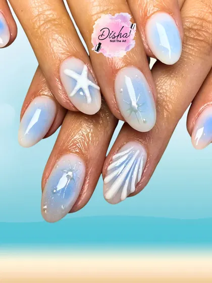 Beach in a manicure. These dreamy nails feature a soft blue base with 3D seashells and starfishes for the perfect summer escape.
