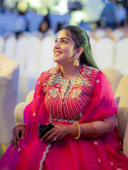 A candid shot of the sister of the bride during an evening event. Her bright pink outfit with intricate collar embroidery is a beautiful example of modern occasion wear that is both festive and unique.