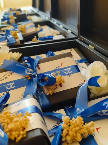 A look inside the milestone hampers, showing individually wrapped gifts with custom-branded ribbons for the "20 Years of Partnership" celebration. Every detail is carefully managed to reflect the corporate identity.
