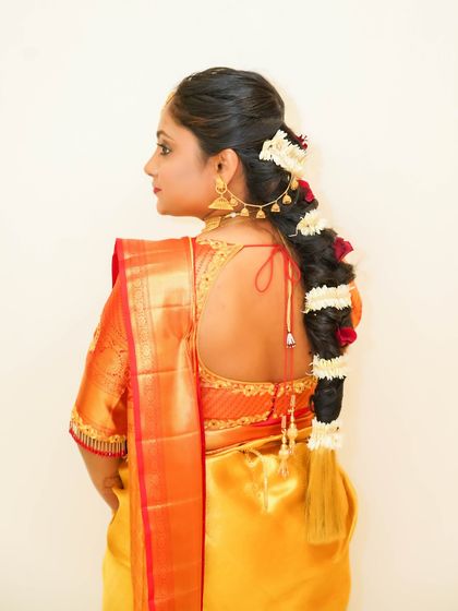 A view of the traditional South Indian bridal hairstyle, featuring a thick braid interwoven with fresh flowers. This is a key part of the complete bridal look I help create.